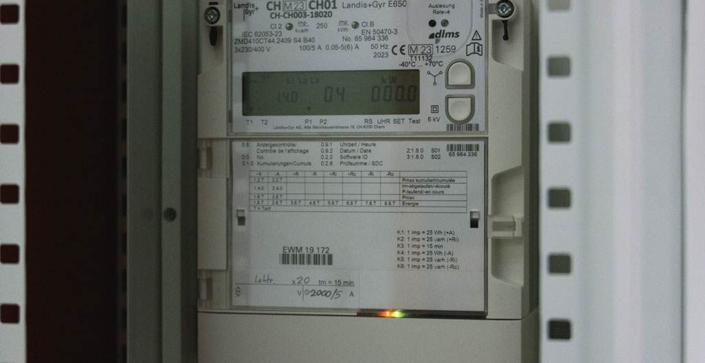 Gros plan d'un boîtier de compteur énergétique moderne monté sur un mur blanc avec câblage visible